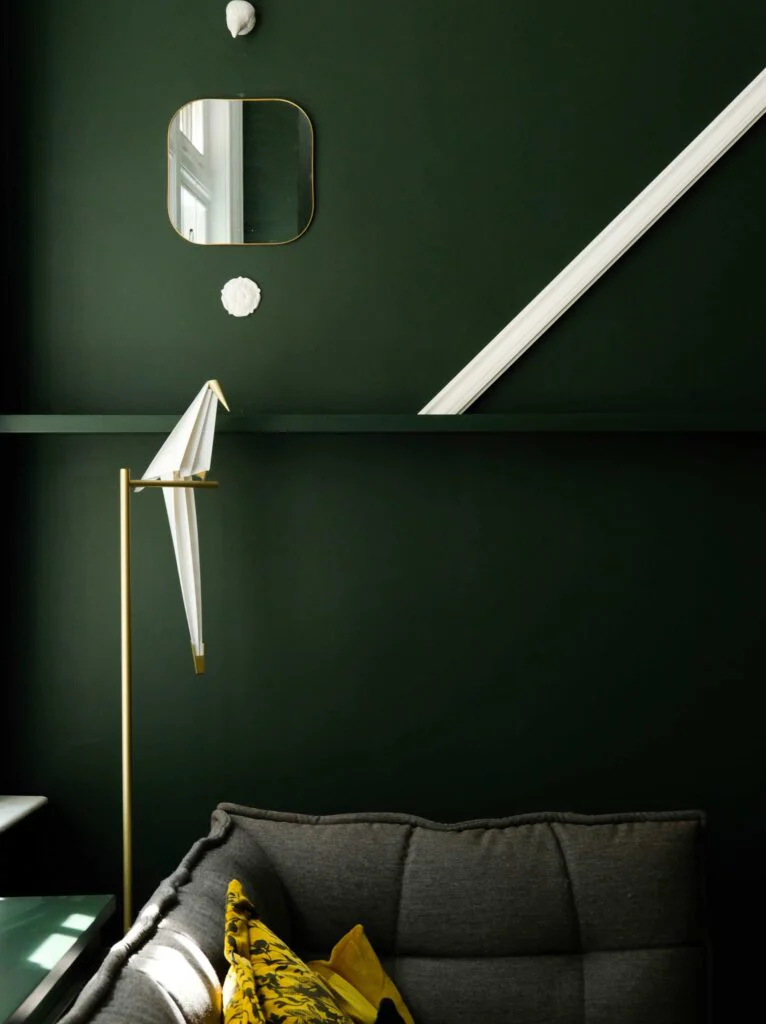 Intérieur au mur vert foncé avec une lampe dorée